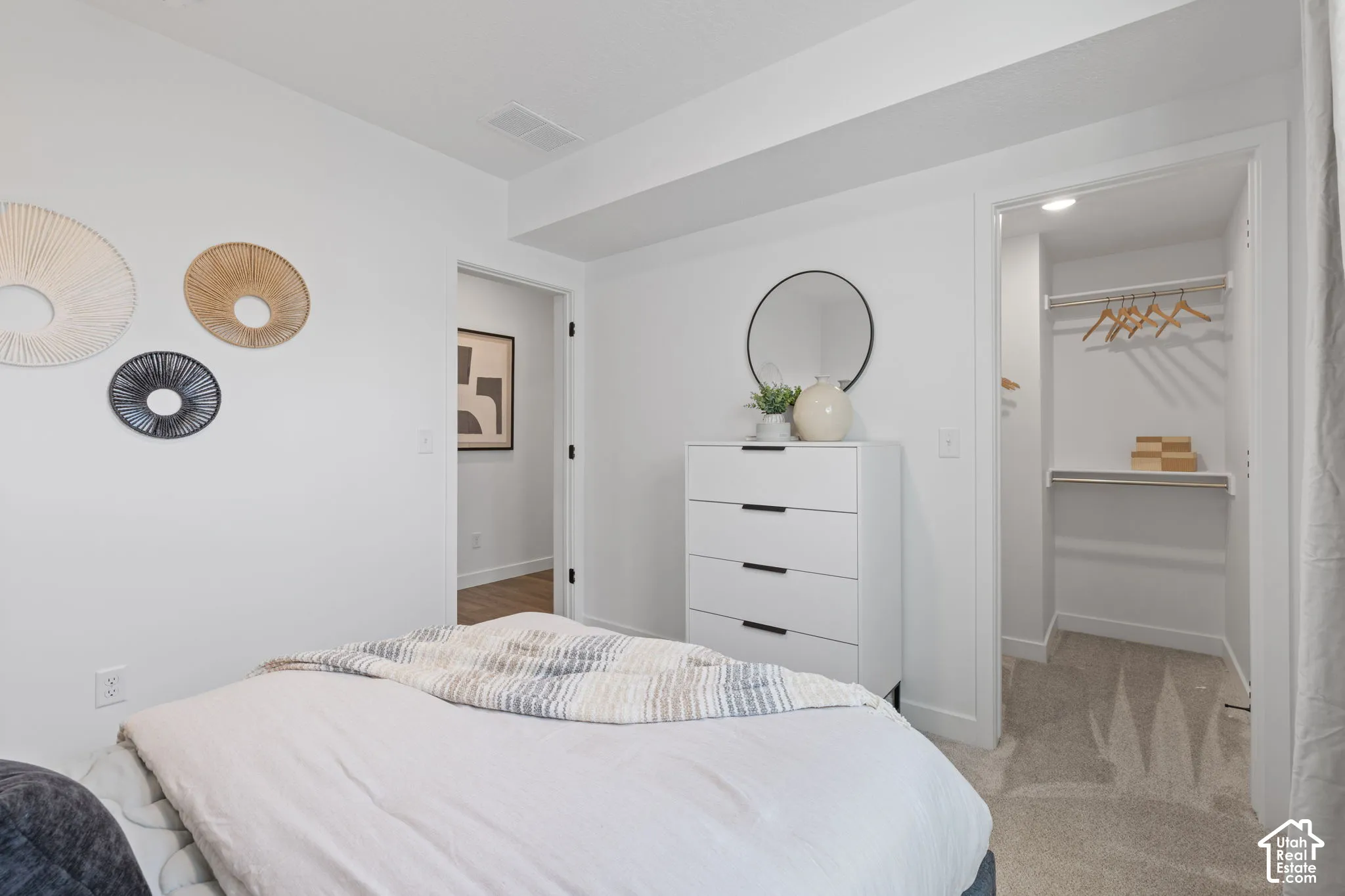 Neutral-toned carpeted flooring, white walls, and a walk-in closet featuring built-in shelving