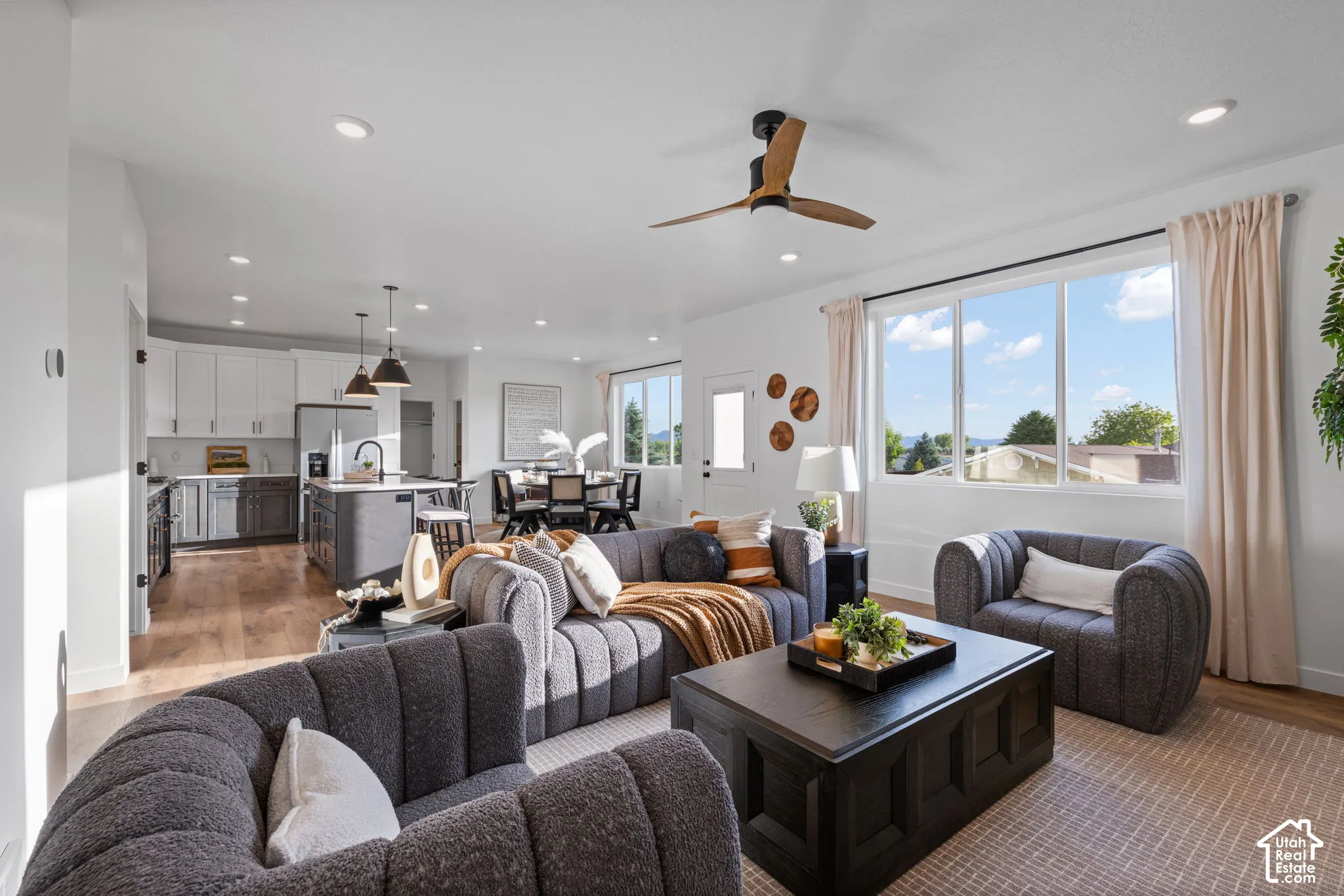 Open-concept space featuring recessed lighting, multi-tone cabinetry, a kitchen island, wood-finish flooring, and a ceiling fan
