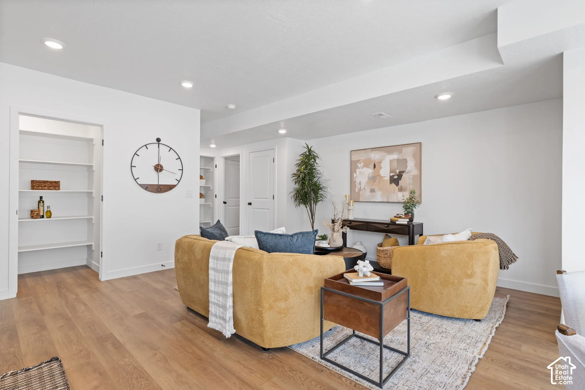 Open-concept living space featuring wood-finish flooring, recessed lighting, built-in shelving, and shaker-style interior doors