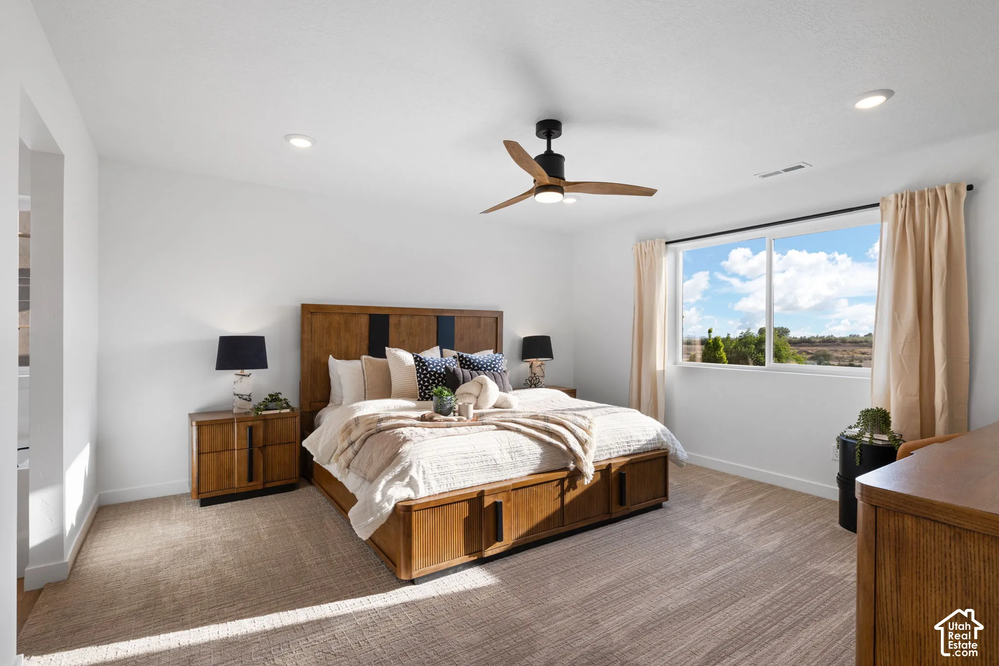Spacious bedroom featuring neutral wall-to-wall carpeting, recessed ceiling lighting, a three-blade matte black ceiling fan, and a large horizontal sliding window