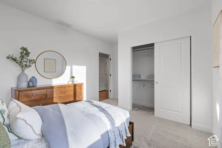 Bedroom featuring neutral wall-to-wall carpeting, a sliding panel closet door, and two-panel interior doors