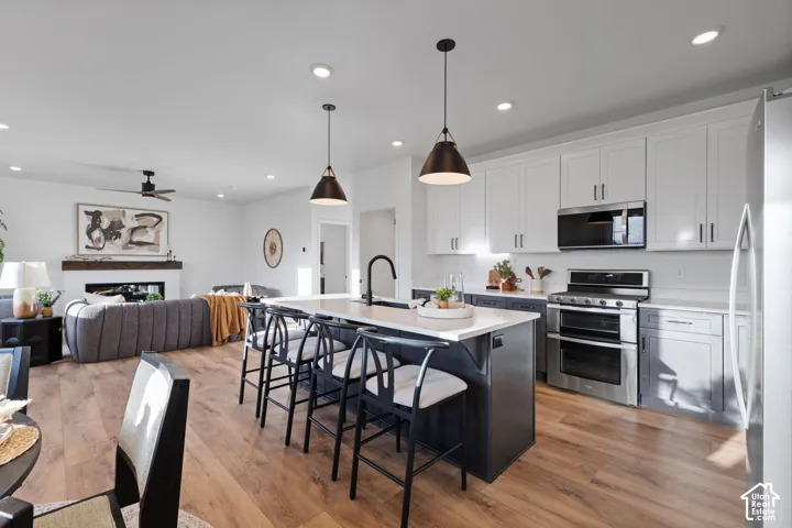 Kitchen featuring shaker-style cabinetry, a central island with a stone-finish countertop, stainless steel appliances, recessed lighting, and wood-finish flooring