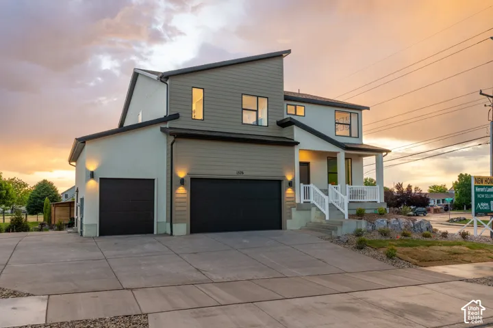Modern exterior featuring a combination of horizontal lap siding and smooth stucco finish, shed-style roofline, three-car garage, and covered front porch with white railings