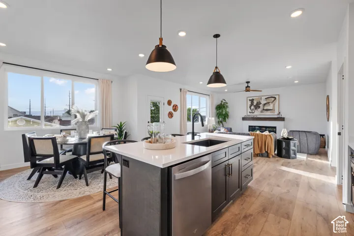 Kitchen featuring a central island with quartz countertops, custom dark-toned cabinetry, stainless steel appliances, wood-finish flooring, and industrial-style pendant lighting