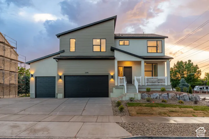 Modern two-story exterior featuring multi-toned siding, a multi-gabled roofline, a three-car garage, and a covered front porch with white railing