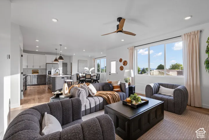 Open-concept space featuring recessed lighting, multi-tone cabinetry, a kitchen island, wood-finish flooring, and a ceiling fan