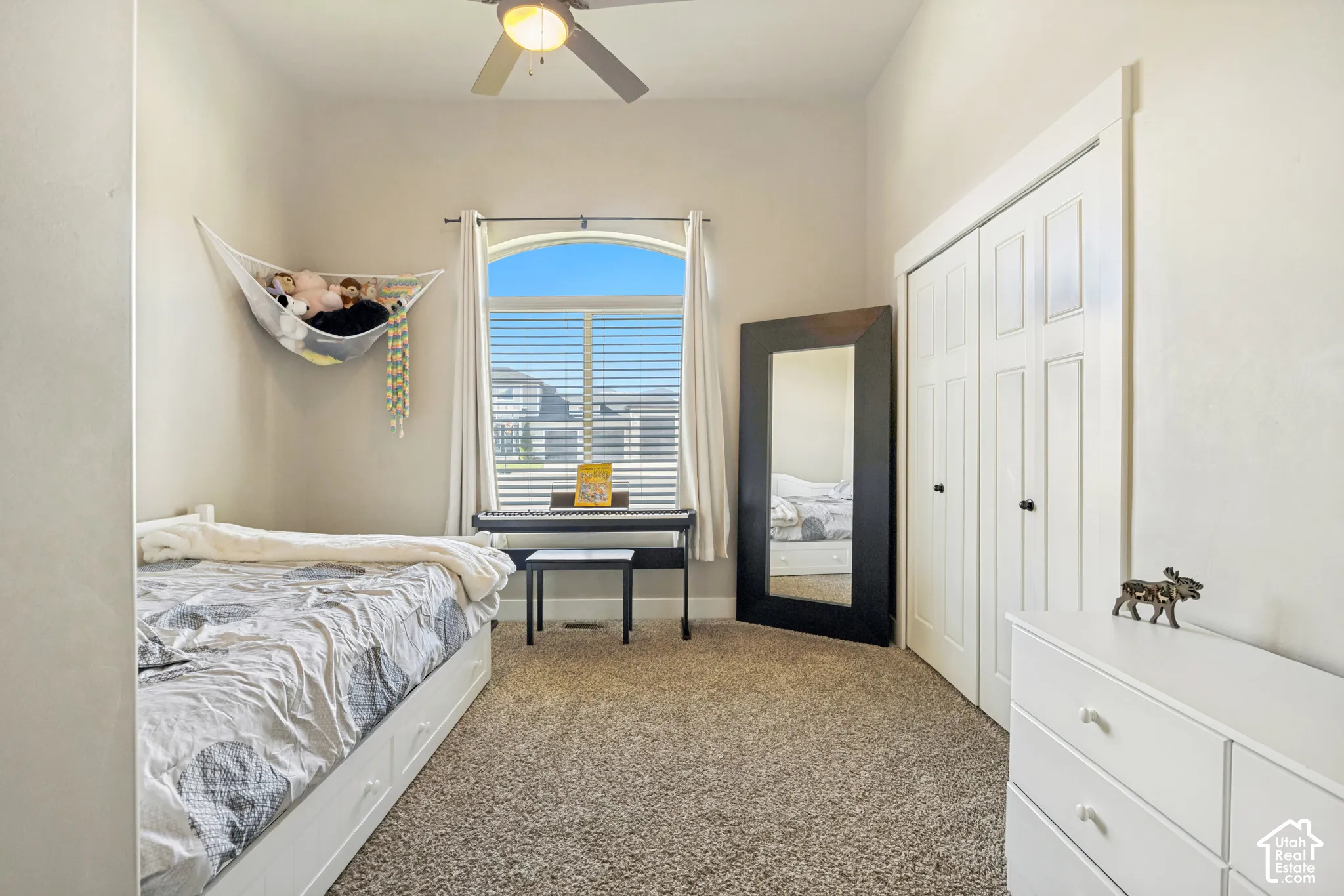 High-ceiling room featuring neutral carpeting, an arched window, and a built-in double-door closet with hardware