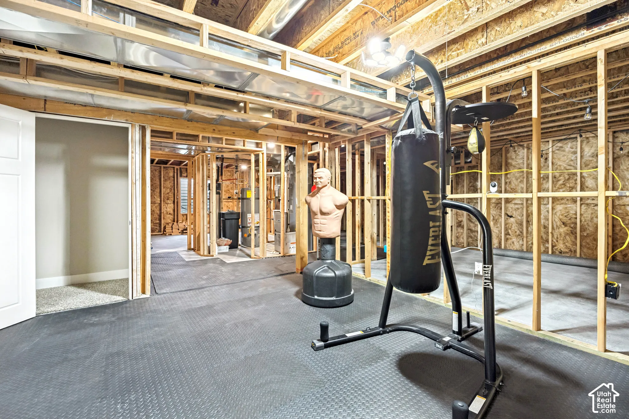 Unfinished lower level featuring exposed wood framing, concrete flooring, exposed ceiling joists, and an installed water heater