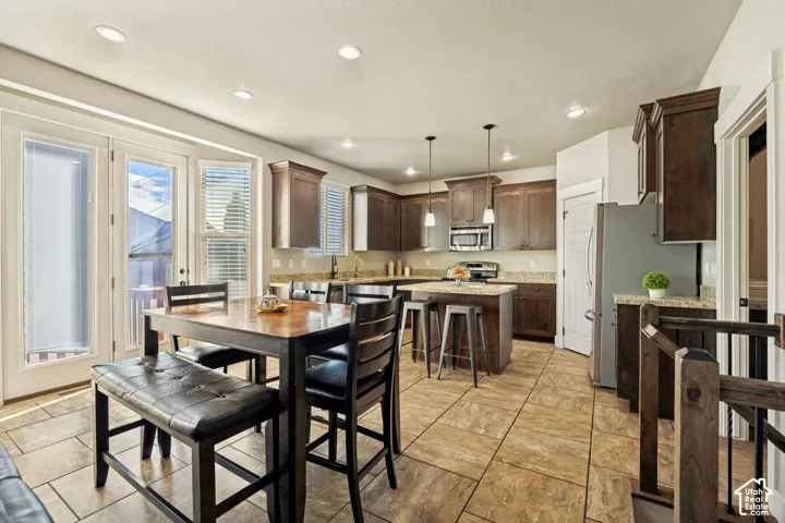 Kitchen featuring dark wood cabinetry, a central island with stone-finish countertops, tile flooring, recessed lighting, and dual glass paneled doors