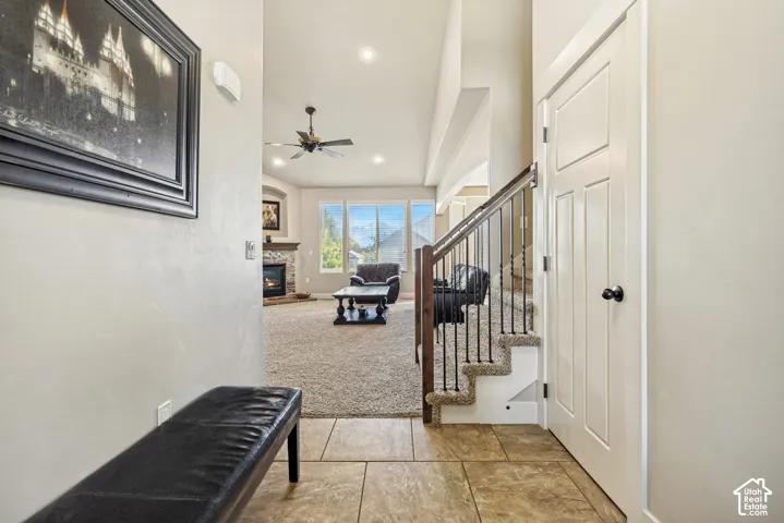 Entryway with large-format tile flooring, carpeted stairs with a dark wood handrail, and wrought-iron balusters