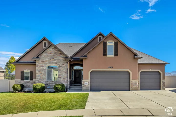 Exterior featuring a stucco and stone veneer facade, a pitched asphalt shingle roof, arched entryway, and a three-car garage