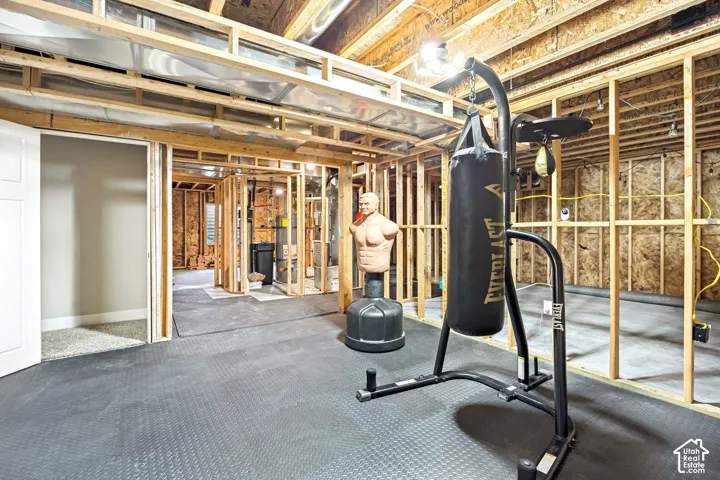 Unfinished lower level featuring exposed wood framing, concrete flooring, exposed ceiling joists, and an installed water heater