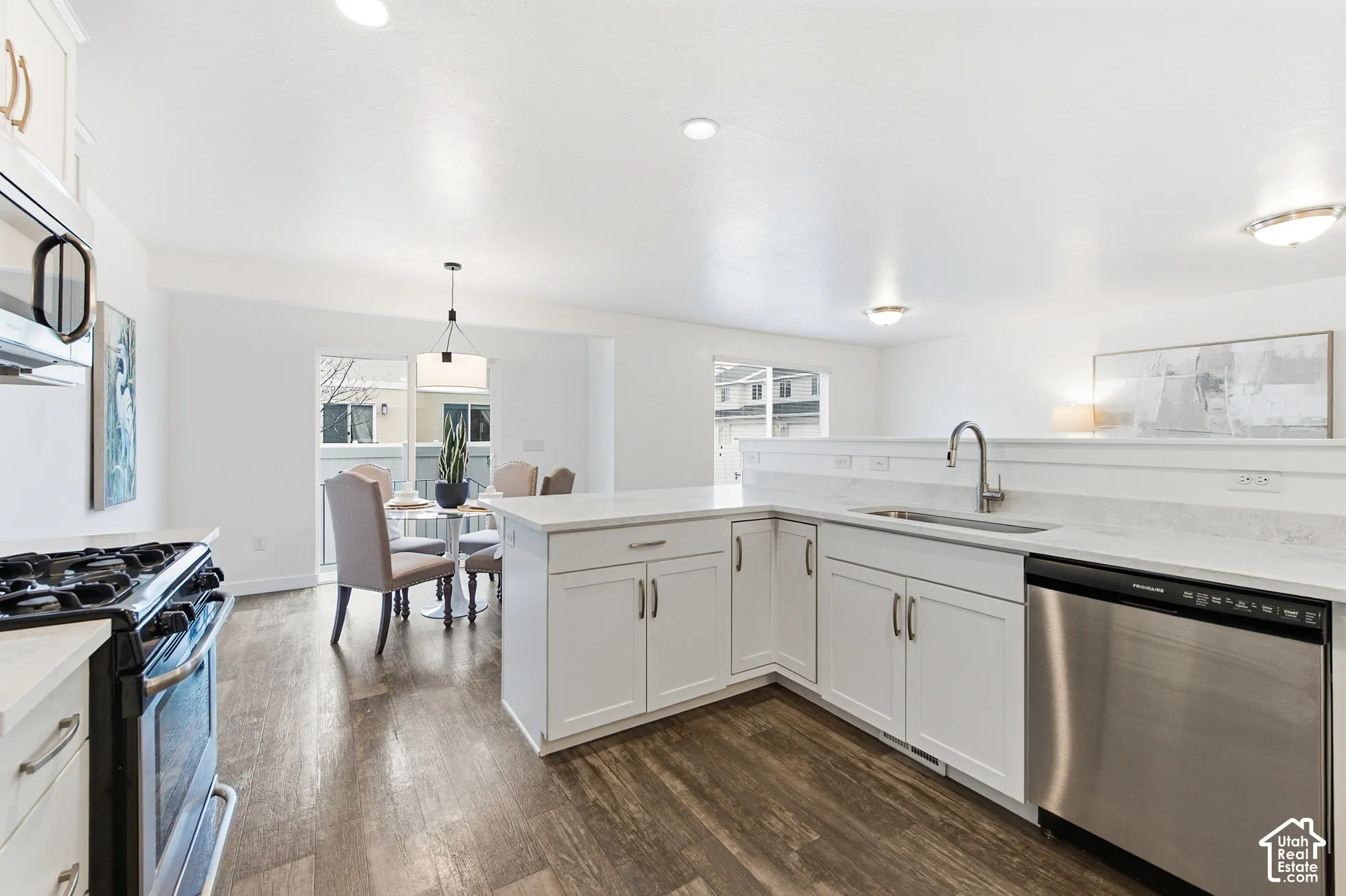 Kitchen featuring white cabinetry, solid surface countertops, stainless steel appliances, and wood-finish flooring with recessed lighting