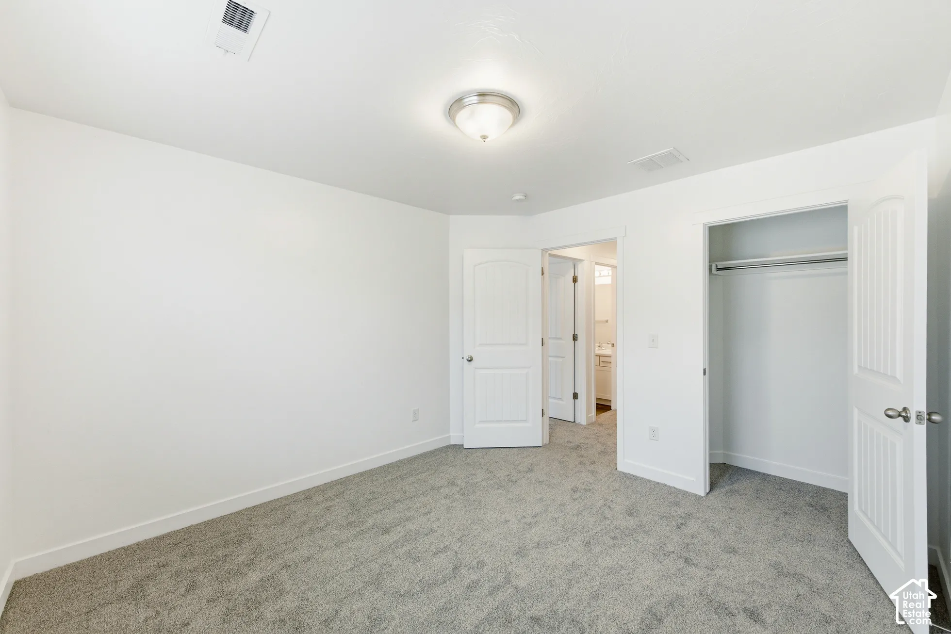 Neutral-toned wall-to-wall carpeting, white interior doors with arched-top detailing, and central ceiling-mounted light fixture