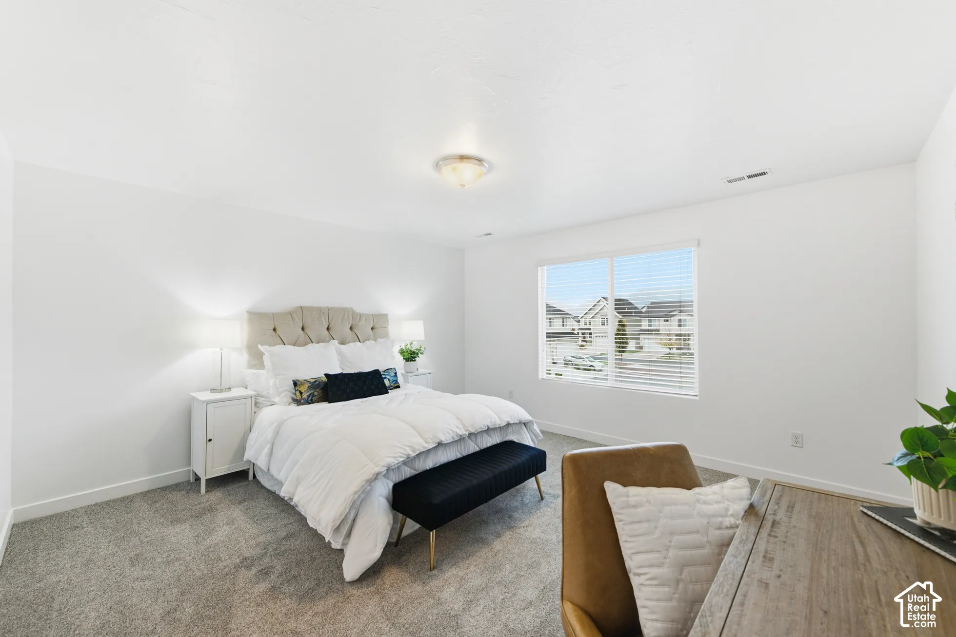 Neutral-toned wall-to-wall carpeting, large window with horizontal blinds, and flush-mount ceiling lighting