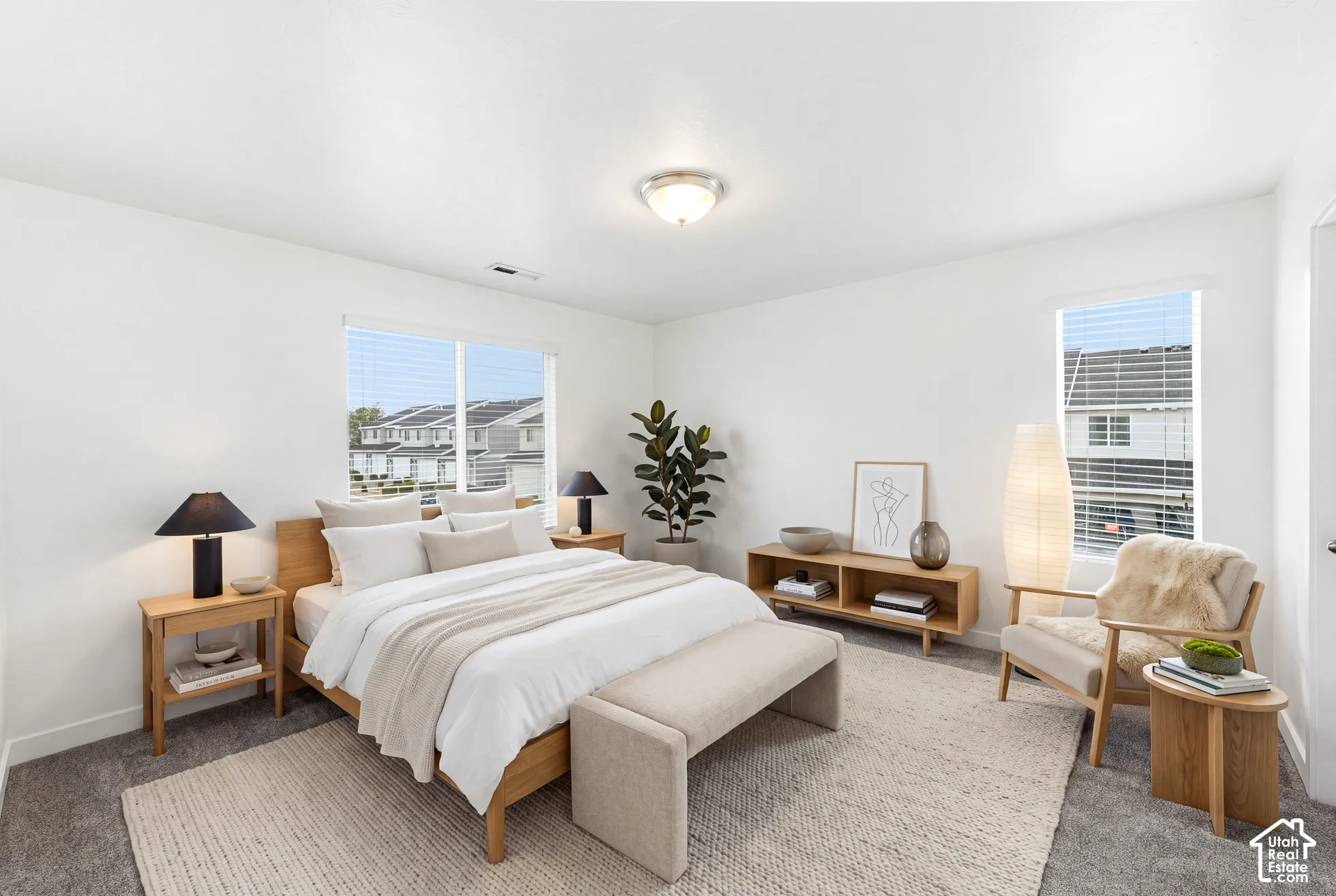 Neutral-toned carpeted flooring, white walls, dual windows with integrated blinds, and a flush-mount ceiling light fixture