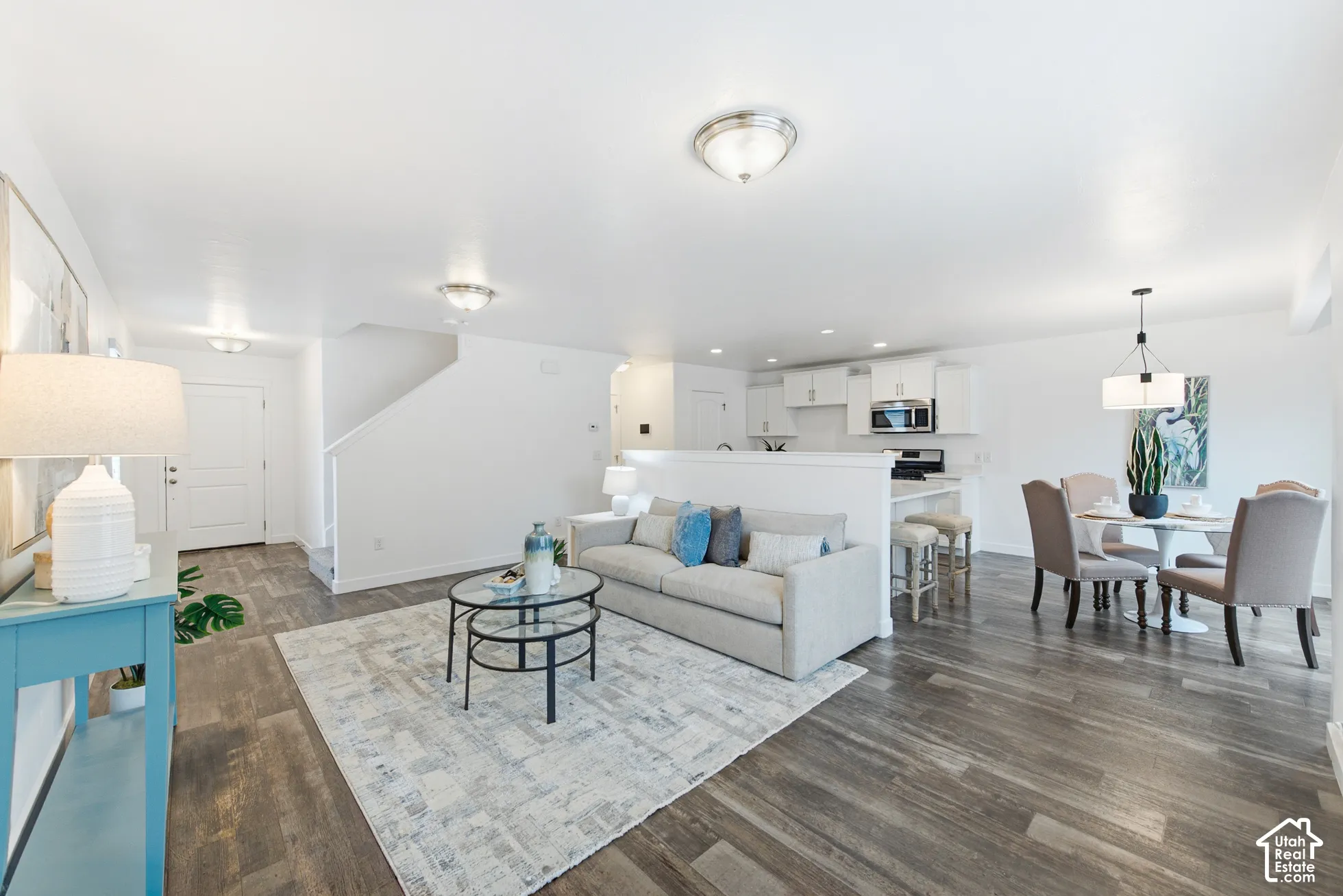Open-concept interior featuring wood-finish flooring, white cabinetry, a breakfast bar, and recessed lighting