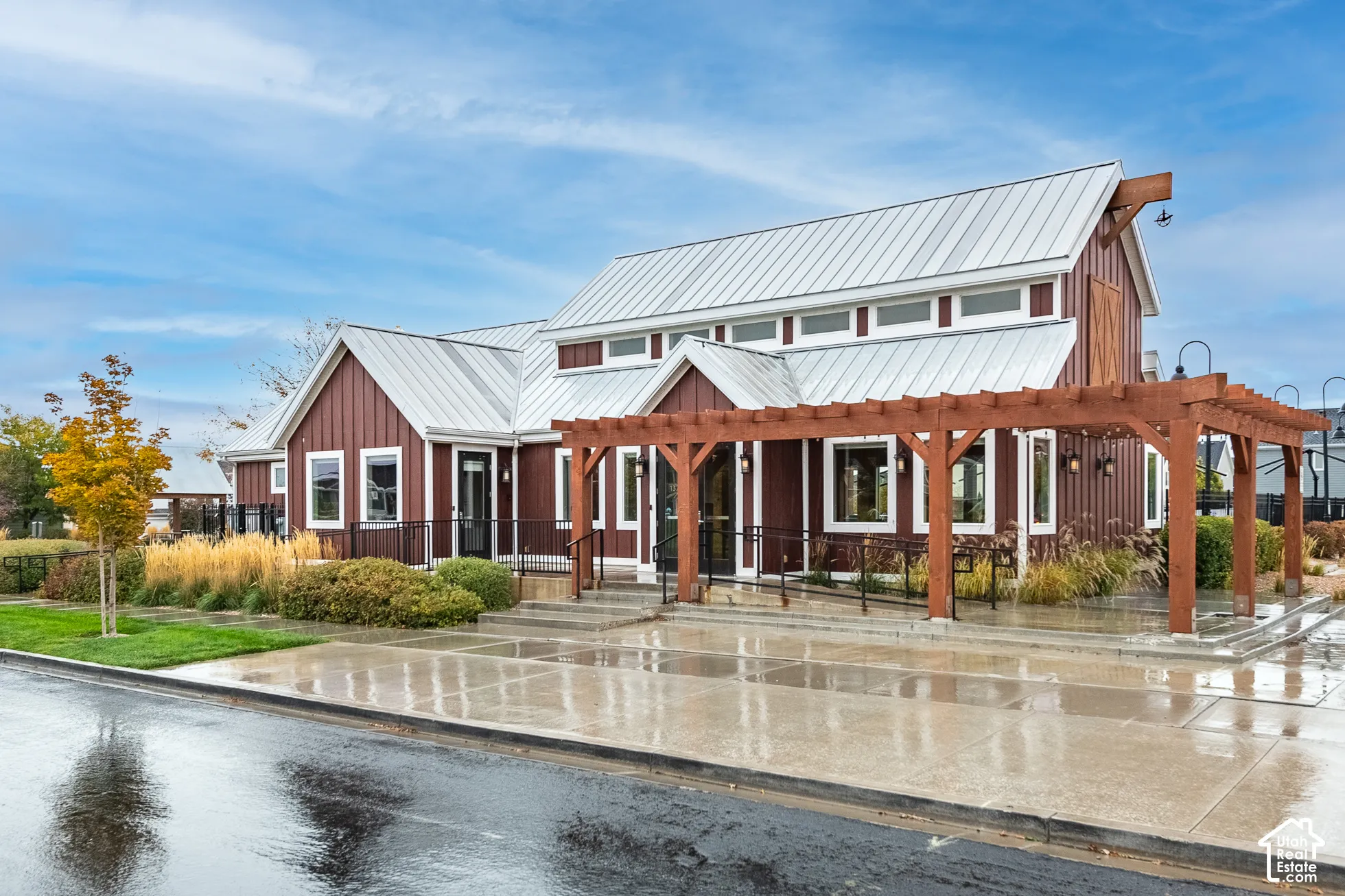 Board-and-batten exterior with a metal roof, prominent wooden pergola, multi-pane windows, and clerestory windows