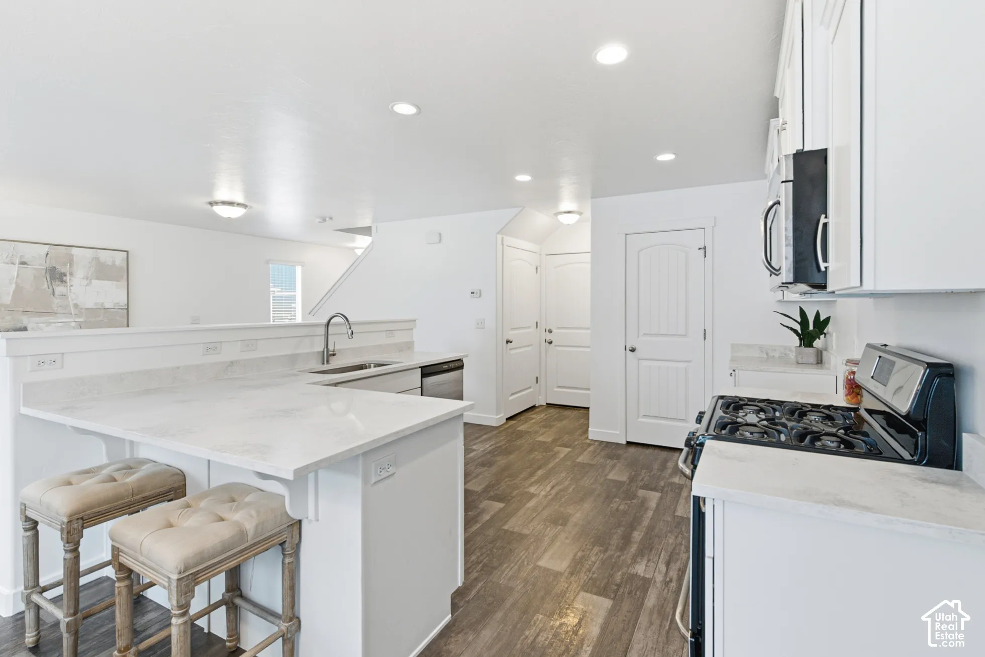 Kitchen featuring white cabinetry, stone-finish countertops, wood-finish flooring, recessed lighting, and a breakfast bar