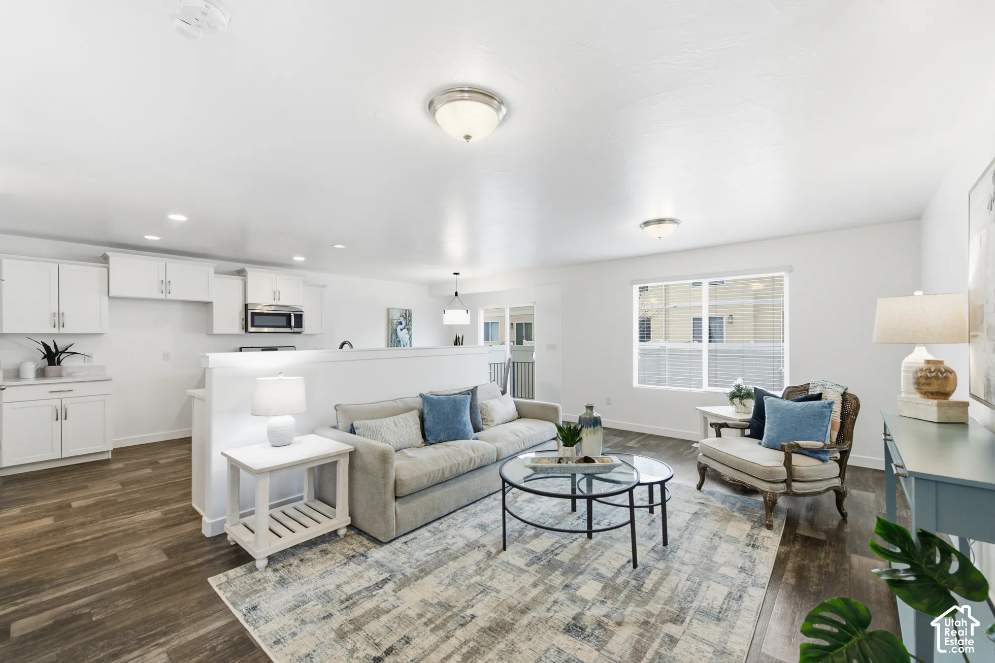 Open-concept area featuring wood-finish flooring, white cabinetry, a built-in stainless steel microwave, and flush-mount lighting fixtures