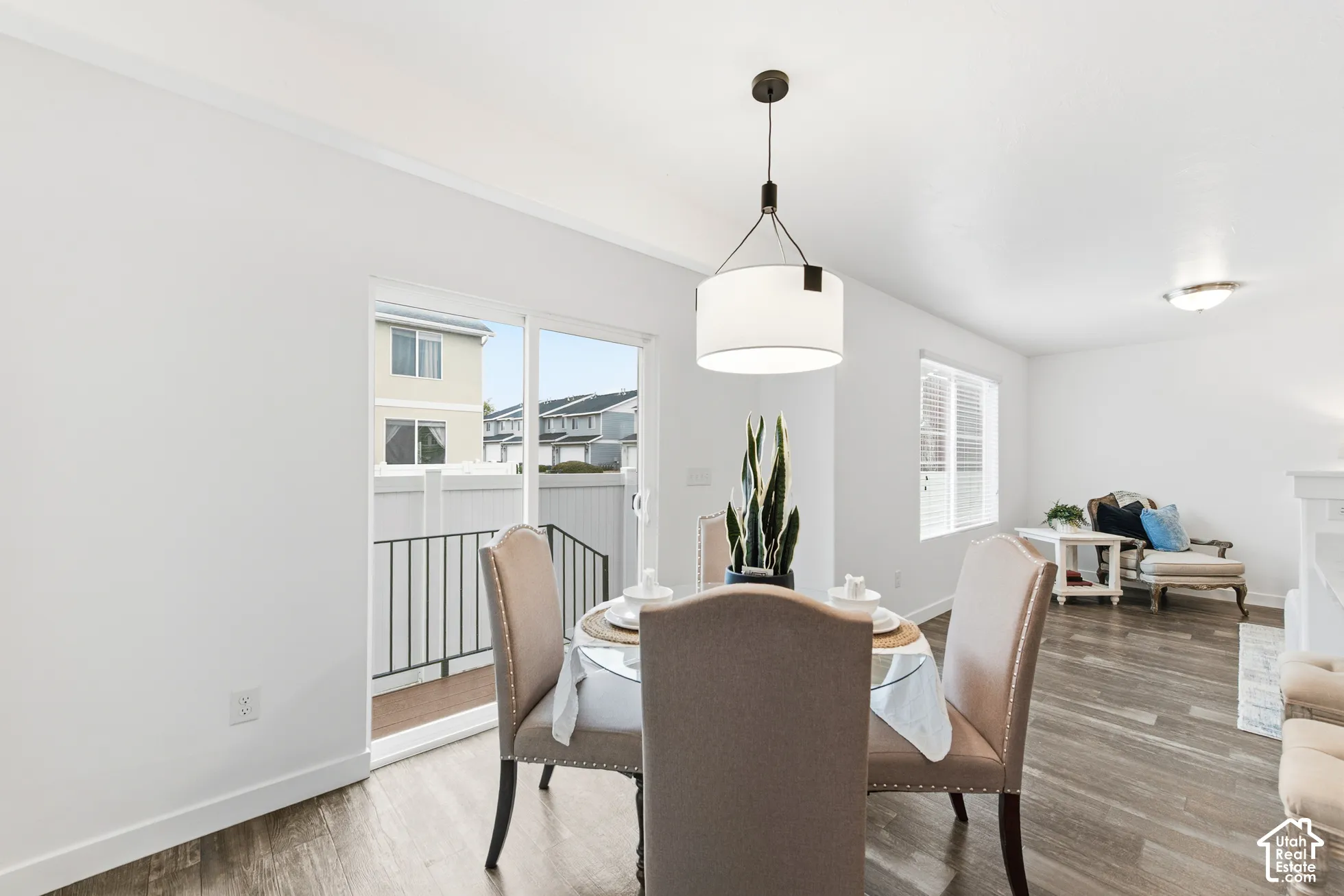 Neutral interior featuring wood-finish flooring, a drum pendant light fixture, and sliding glass doors leading to an exterior balcony
