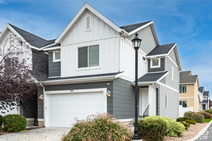 Exterior featuring a combination of lap and board-and-batten siding, an asphalt shingle roof, a single-car garage, and a decorative post lamp