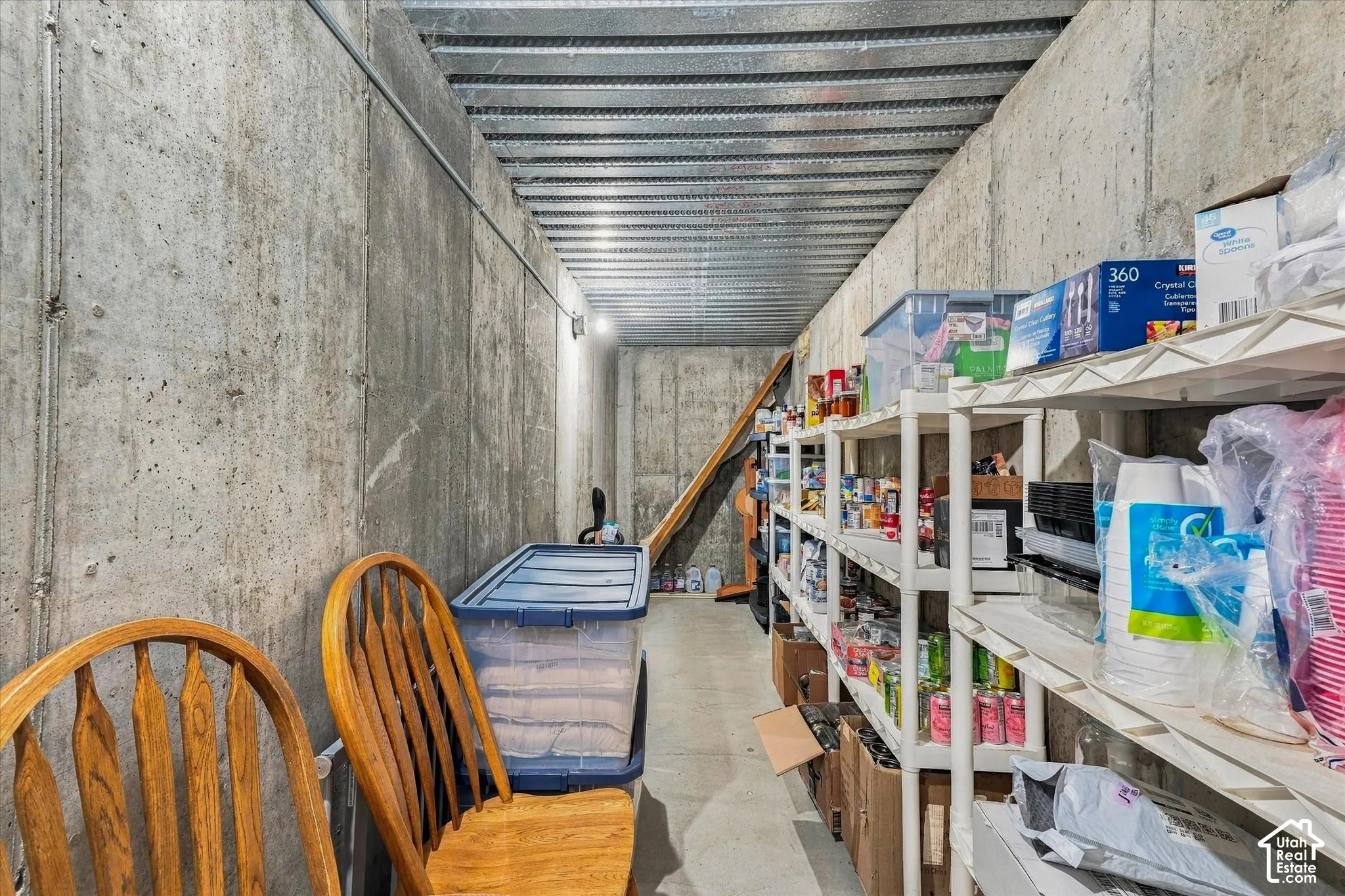 Storage area featuring poured concrete walls and a corrugated metal ceiling