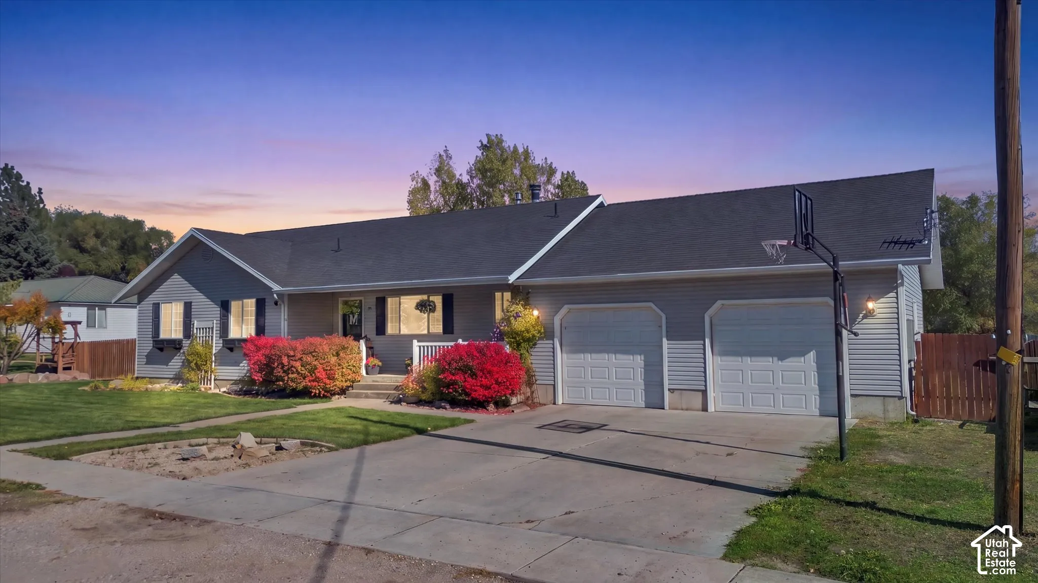 Single-story residence featuring a light-colored horizontal siding exterior, a dark asphalt shingle roof, a two-car garage, and a manicured front lawn