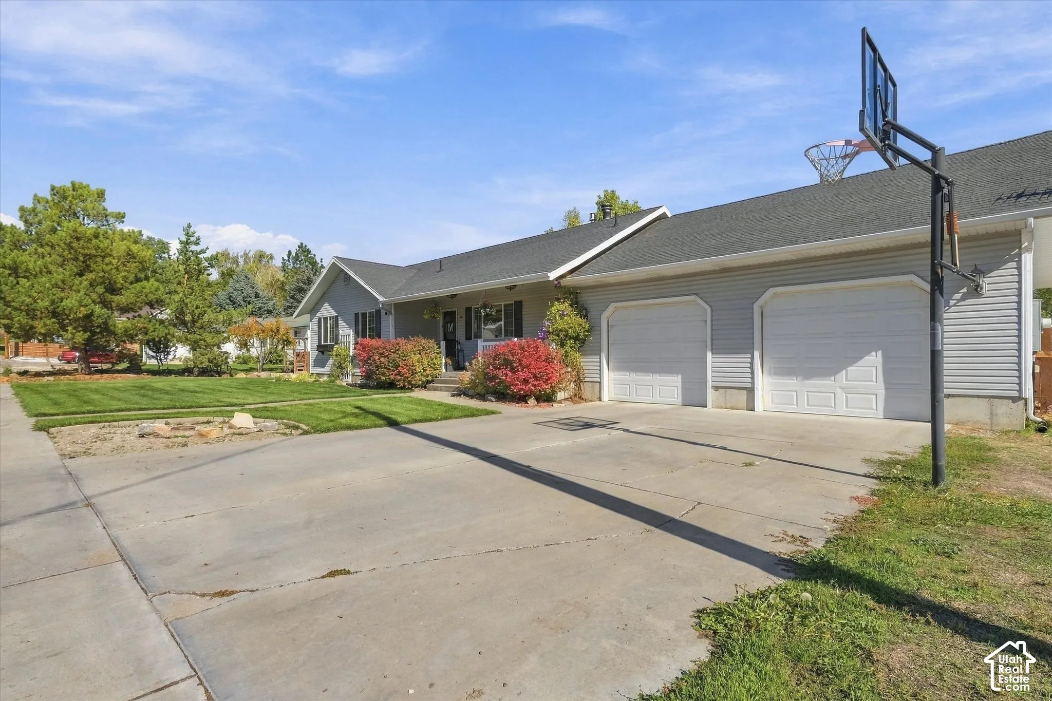 Single-story residence featuring light gray siding, an asphalt shingle roof, a two-car garage, and a concrete driveway