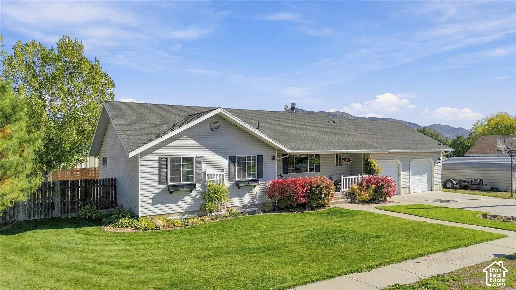 Single-story exterior featuring horizontal siding, a pitched roof, two-car garage, window boxes, and a backdrop of mountain scenery