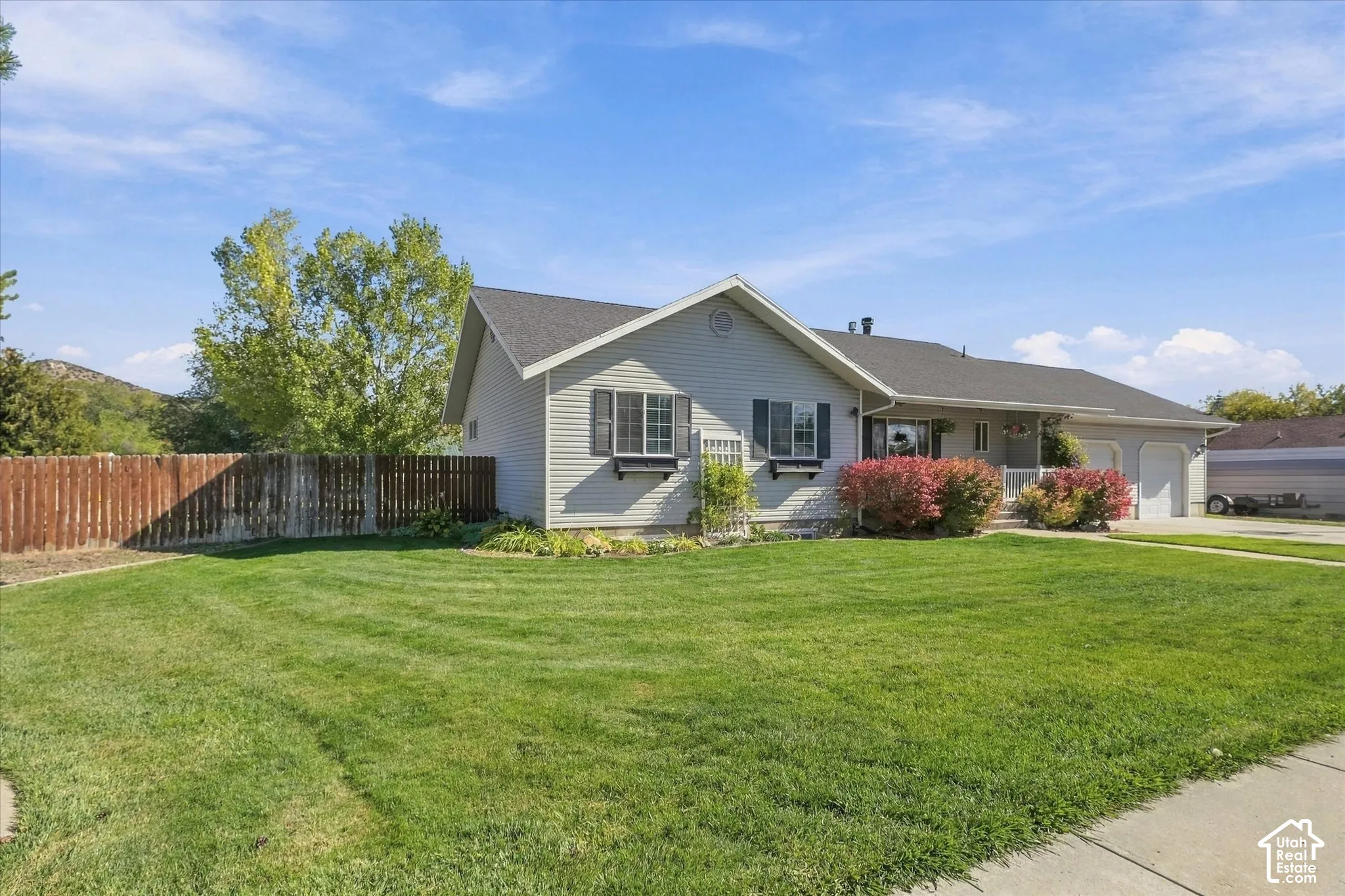 Single-level residence with light-colored siding, shingle roofing, window shutters, flower boxes, and a two-car garage