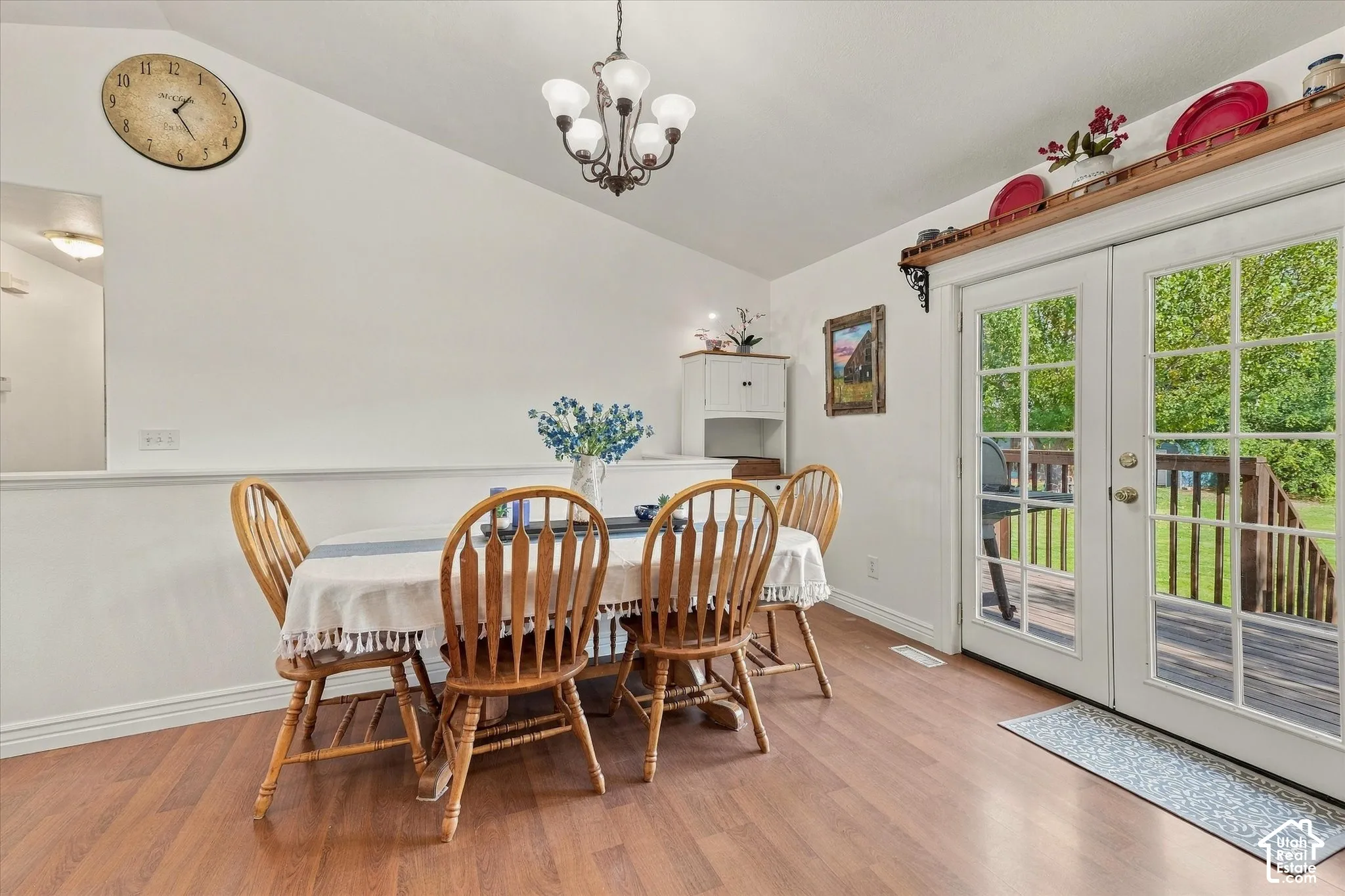 Vaulted ceiling, wood-finish flooring, built-in wall niche shelving, multi-light chandelier, and full-glass paneled double doors