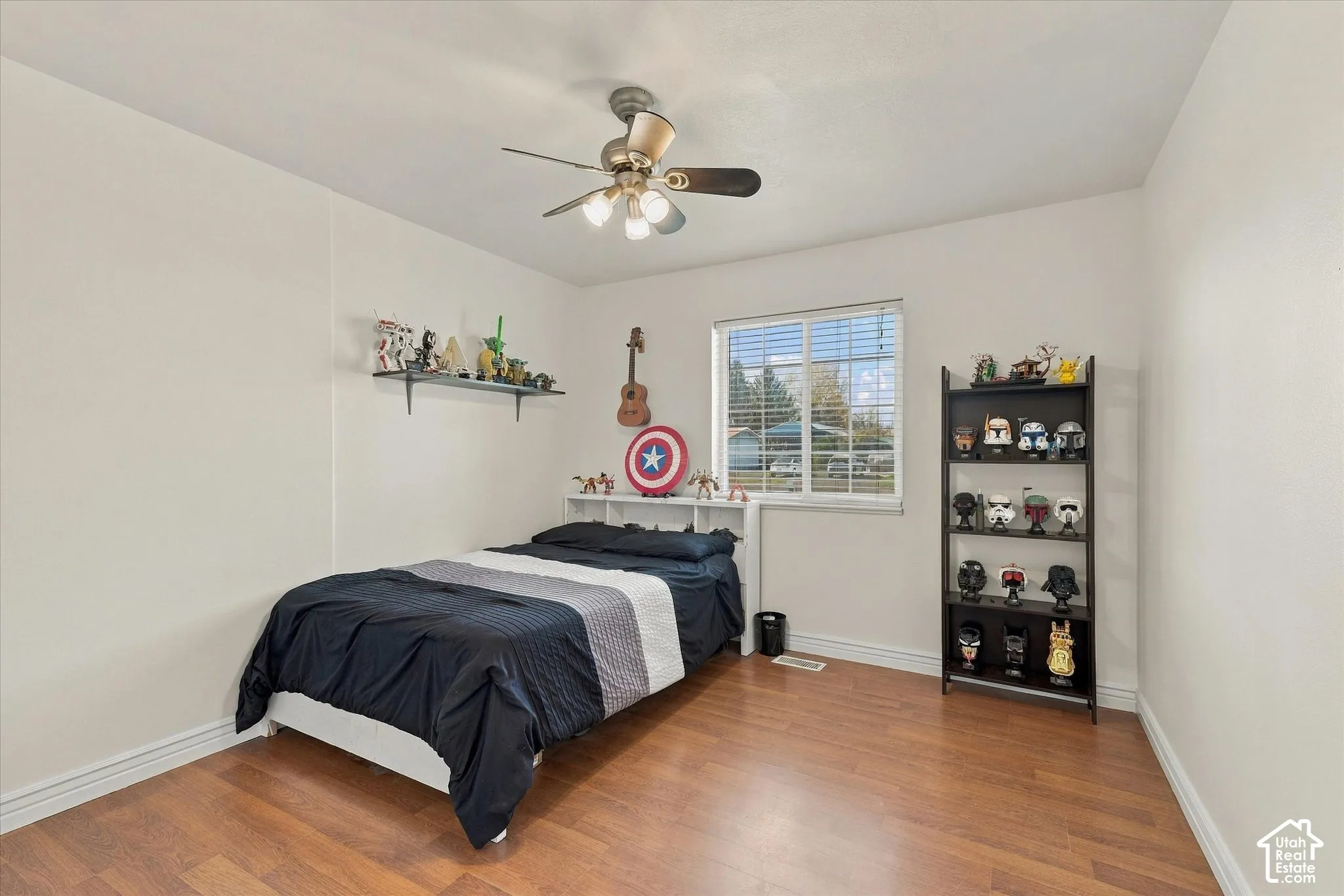 Neutral interior space featuring wood-finish flooring, a ceiling fan with integrated lighting, and a single-pane window