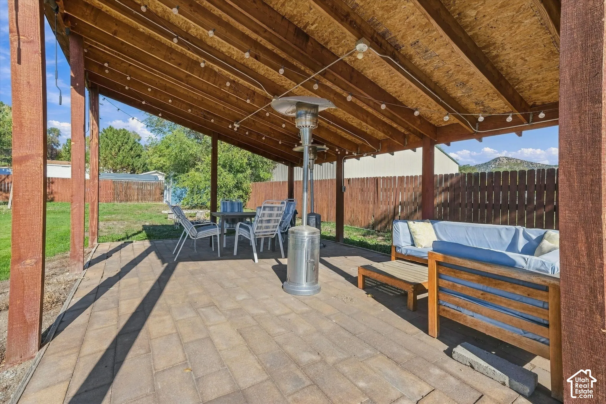 Covered patio featuring a wood-beam ceiling, concrete paver flooring, and wood-slat perimeter fencing