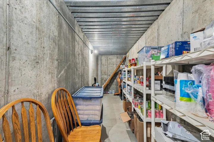 Storage area featuring poured concrete walls and a corrugated metal ceiling