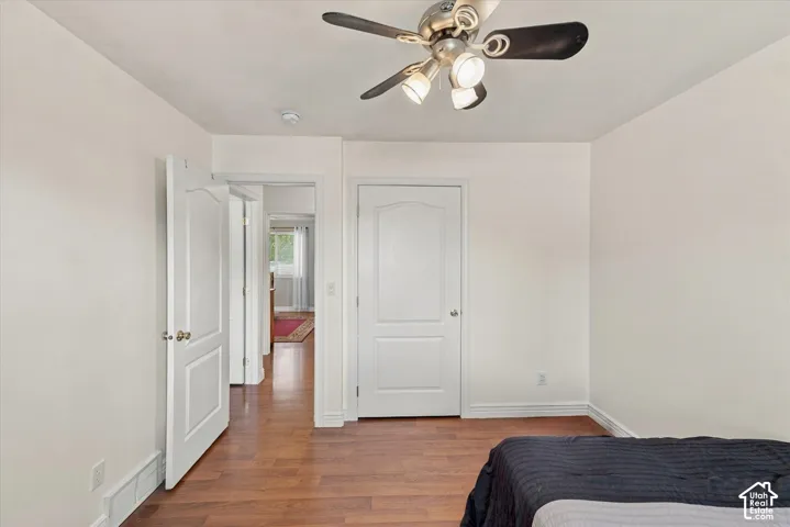 Wood-finish flooring, white paneled interior doors, and a ceiling fan with integrated lighting