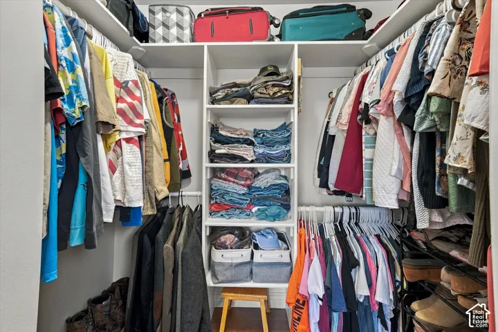 Walk-in closet featuring white built-in shelving, a central column of open storage cubbies, and tiered hanging rods