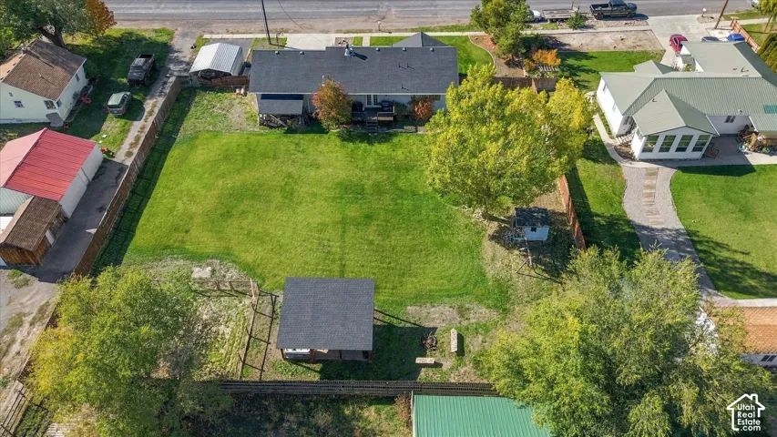 Expansive backyard featuring a large grass lawn, mature trees, a detached covered structure, and full perimeter fencing