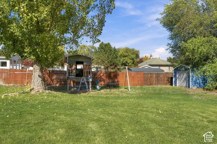 Expansive backyard featuring a mature shade tree, perimeter wood fencing, and a detached storage structure