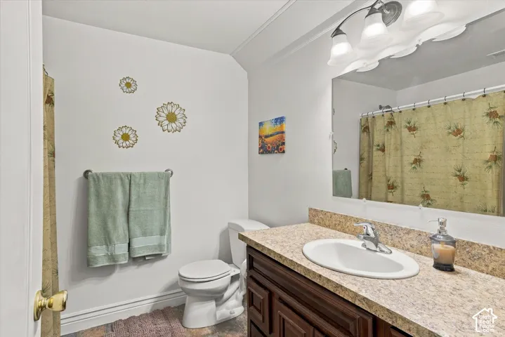 Bathroom featuring a vanity with a stone-patterned countertop, an undermount oval sink, chrome faucet hardware, a large frameless wall-mounted mirror, and multi-bulb overhead lighting