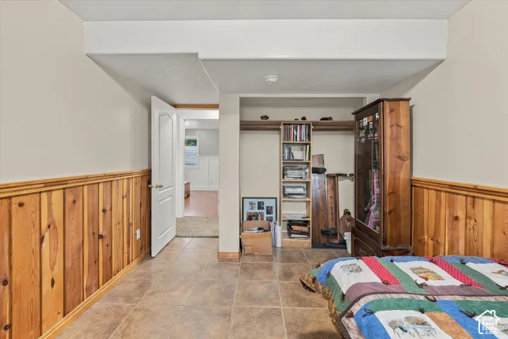 Interior space featuring tile flooring, wood paneling on the lower walls, and built-in vertical shelving
