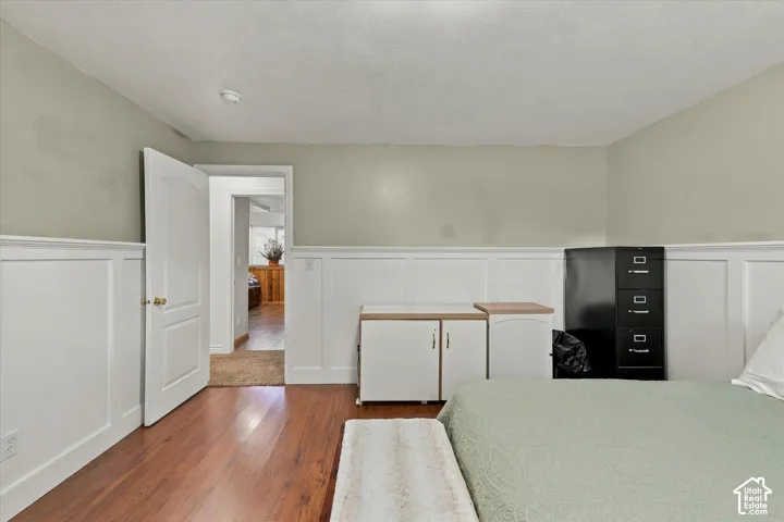 Interior room featuring white wainscoting, wood-finish flooring, and a six-panel interior door