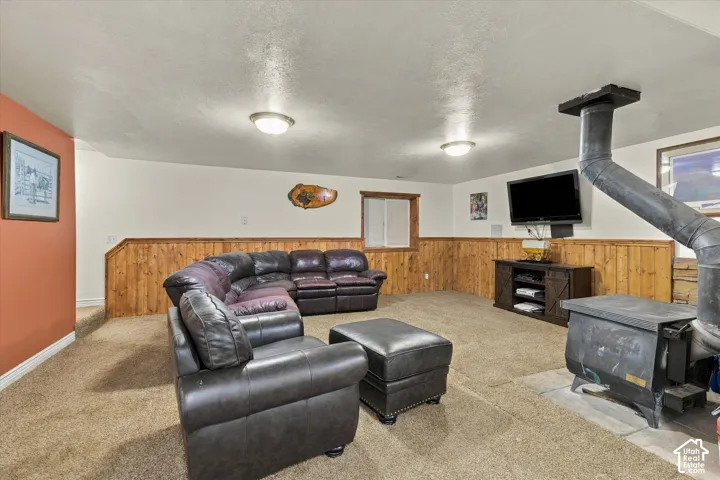 Wood-paneled wainscoting, wall-mounted wood-burning stove with metal flue, and recessed ceiling lighting