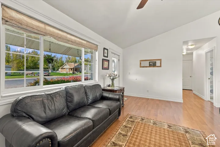 Vaulted ceiling, large picture window with muntins, wood-finish flooring, and recessed ceiling lighting