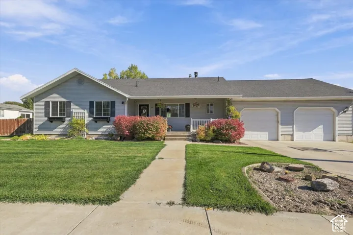 Single-story residence featuring light-toned horizontal siding, a two-car attached garage, asphalt shingle roofing, window flower boxes, and a concrete walkway