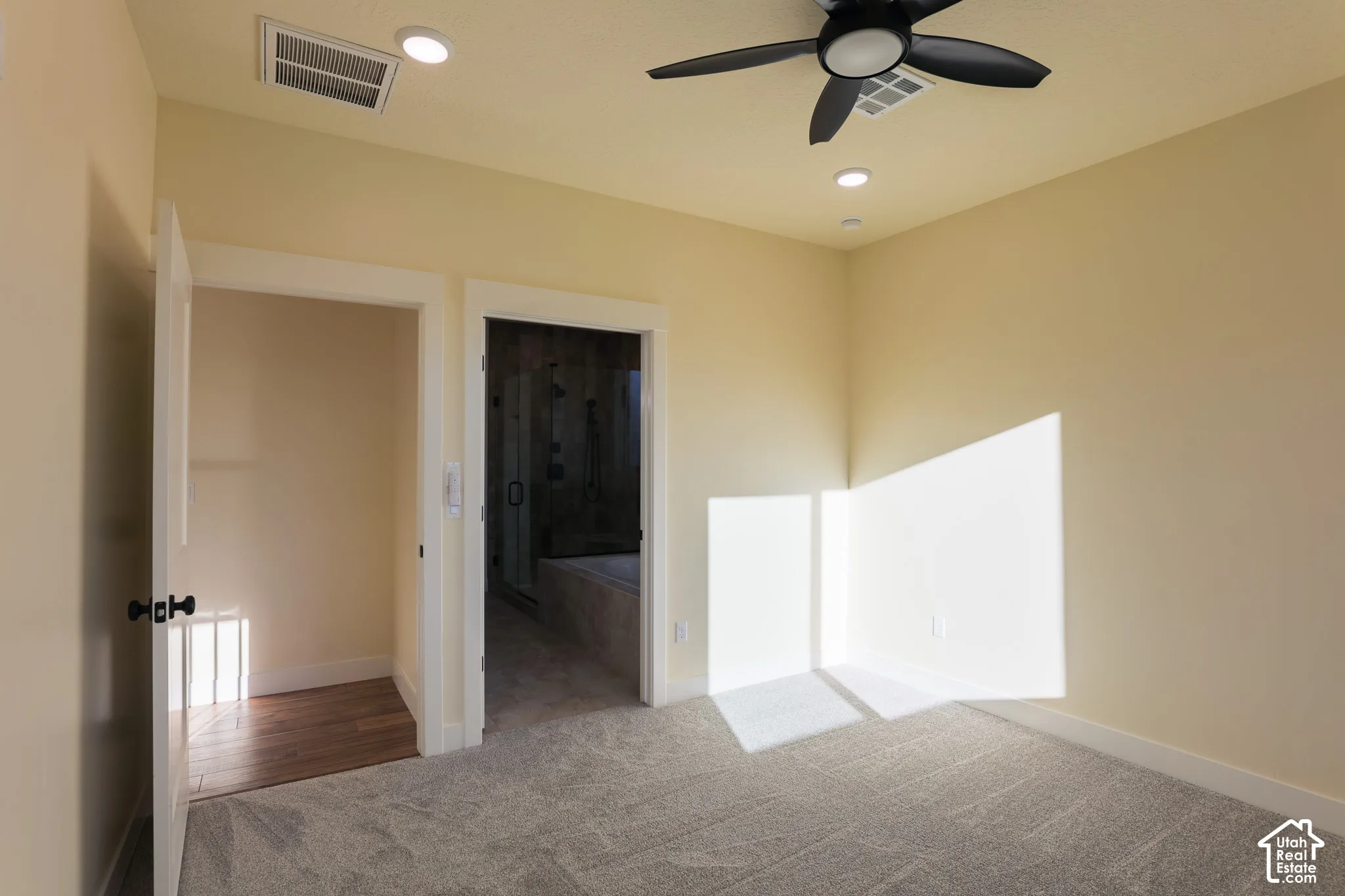 Neutral-toned interior featuring wall-to-wall carpeting, a multi-blade ceiling fan, recessed lighting, and wood-finish flooring in the entryway