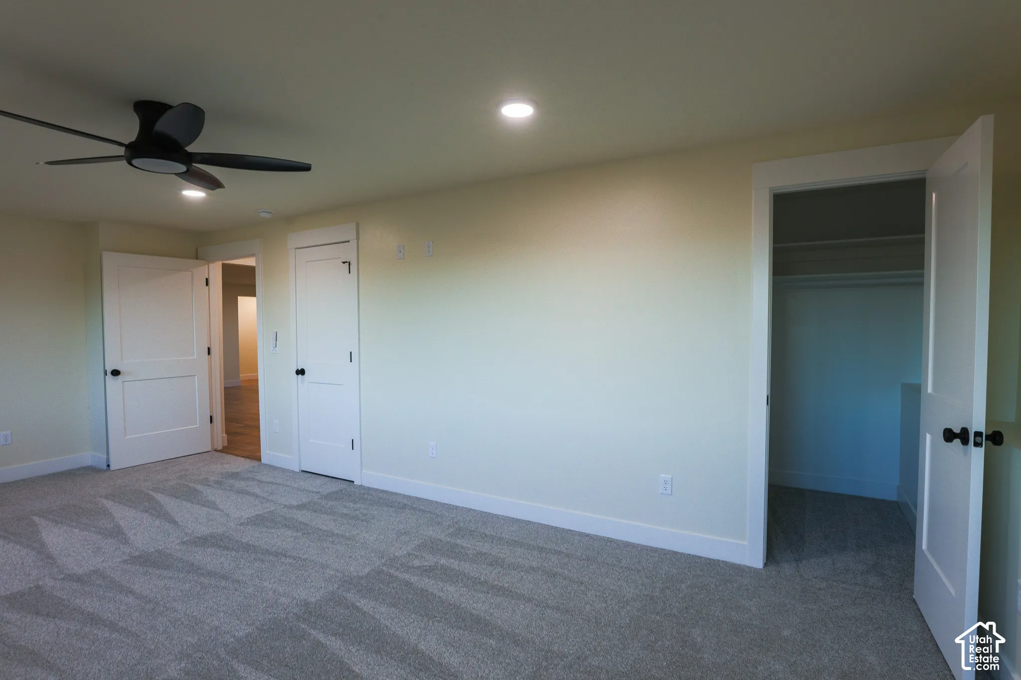 Room featuring neutral carpeting, recessed lighting, a modern ceiling fan, multi-panel doors with matte black hardware, and an integrated closet