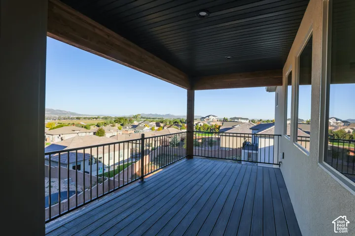 Covered balcony with composite decking, black metal railing, dark wood-tone soffit, and recessed lighting