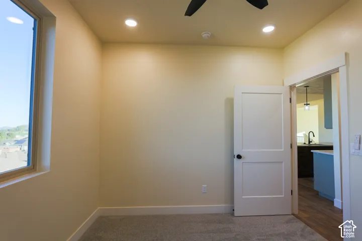 Neutral-toned interior space featuring wall-to-wall carpeting, recessed ceiling lighting, a ceiling fan, and a multi-pane window