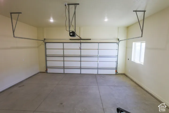 Garage interior featuring a concrete floor, finished walls, recessed lighting, and a single-pane window